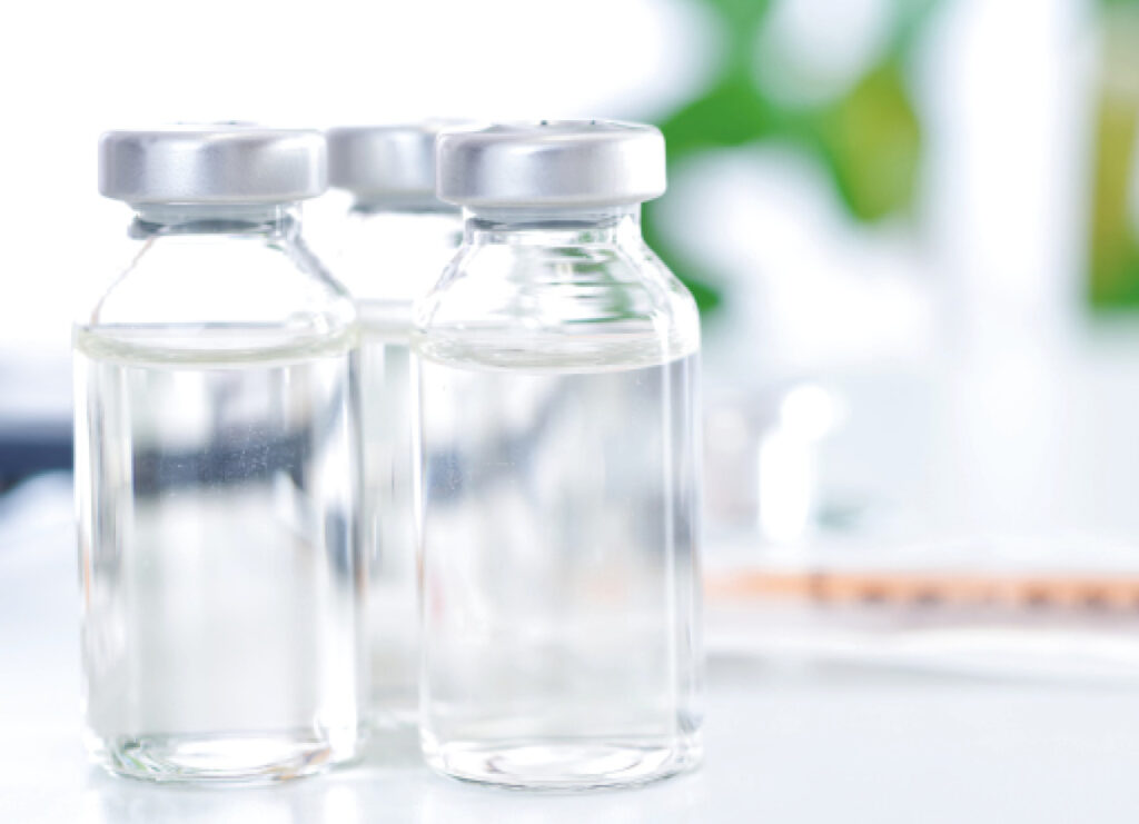 Tres botellas de vidrio con líquido transparente en un fondo desenfocado