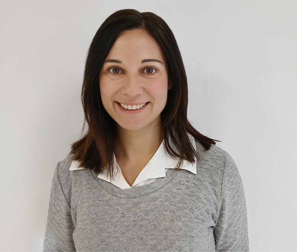 Mujer sonriendo con camiseta gris y camisa blanca