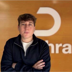 Marc Bautista, especialista en marketing digital en Dechra, posando frente al logo de la empresa.