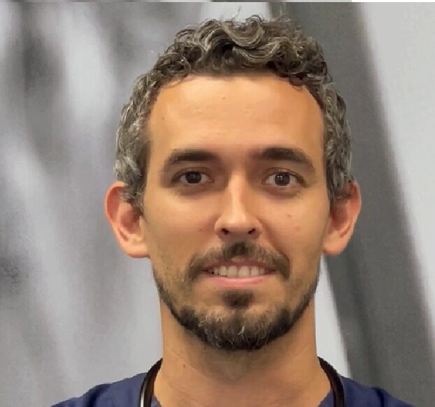 Médico con estetoscopio sonriendo en un entorno clínico
