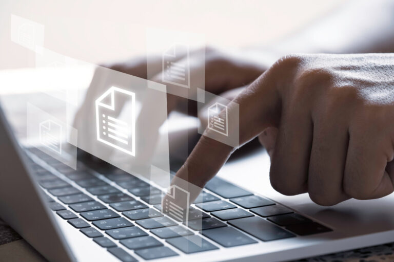 Persona usando un teclado de laptop con documentos digitales flotando