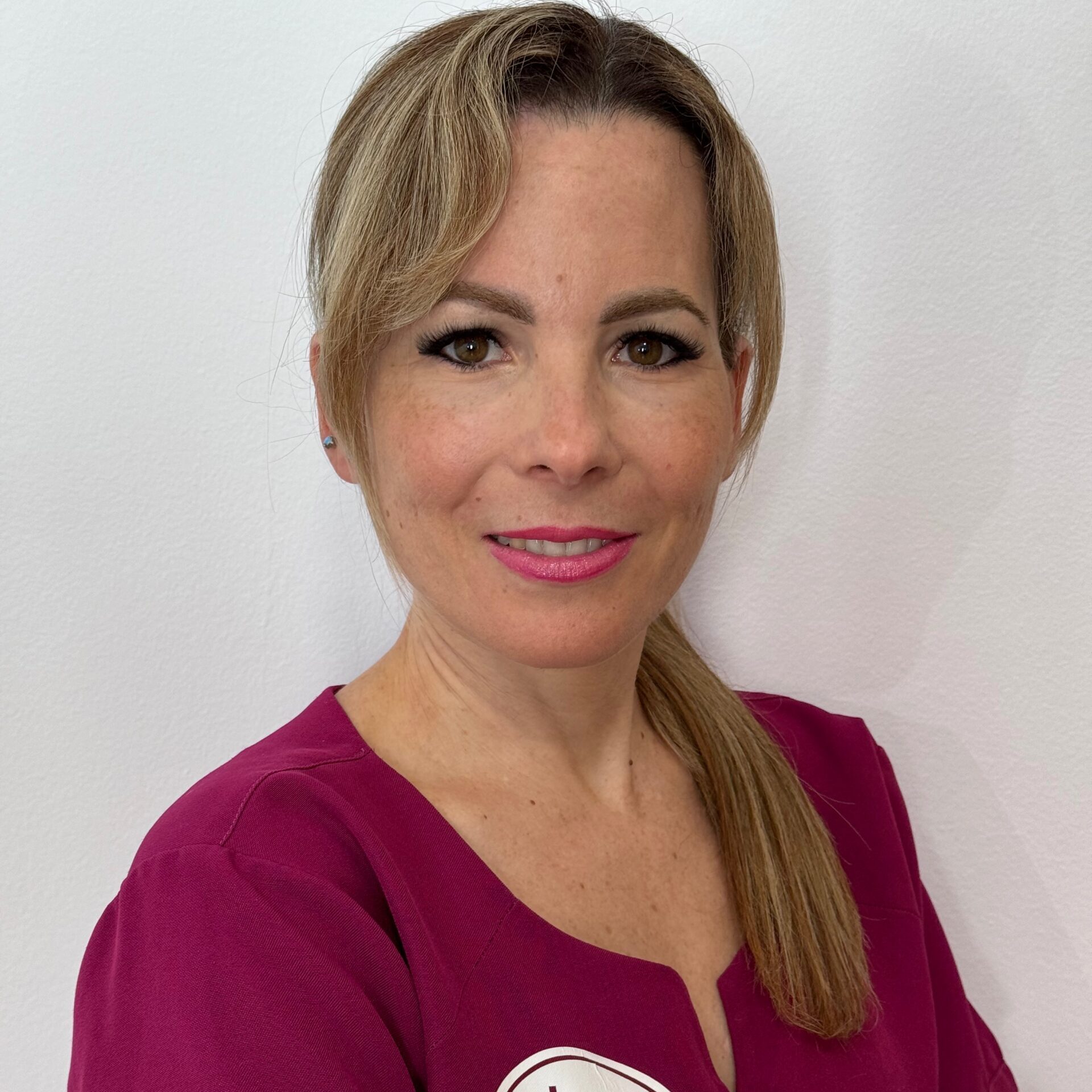 Mujer con uniforme de color púrpura sonriendo a la cámara