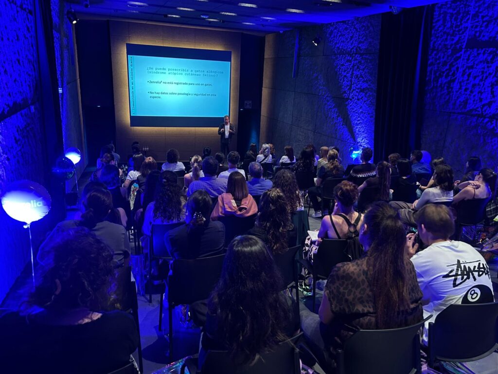 Asistentes a una charla sobre salud en Bilbao con un ponente en el escenario.