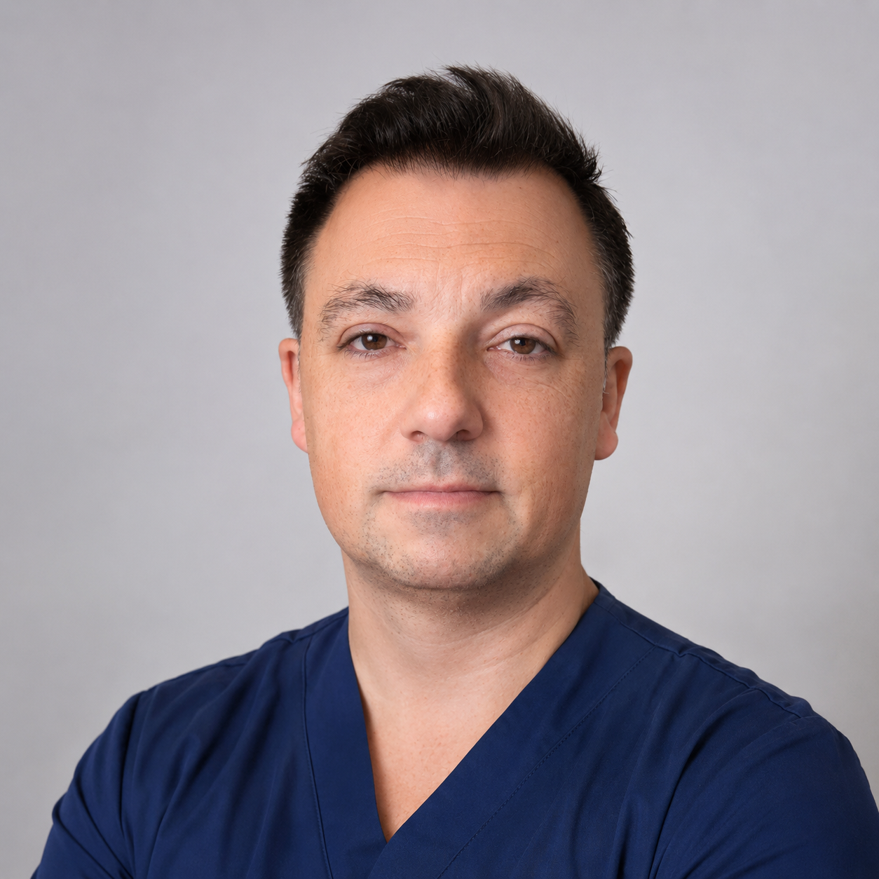 Retrato de un médico con uniforme azul frente a fondo gris