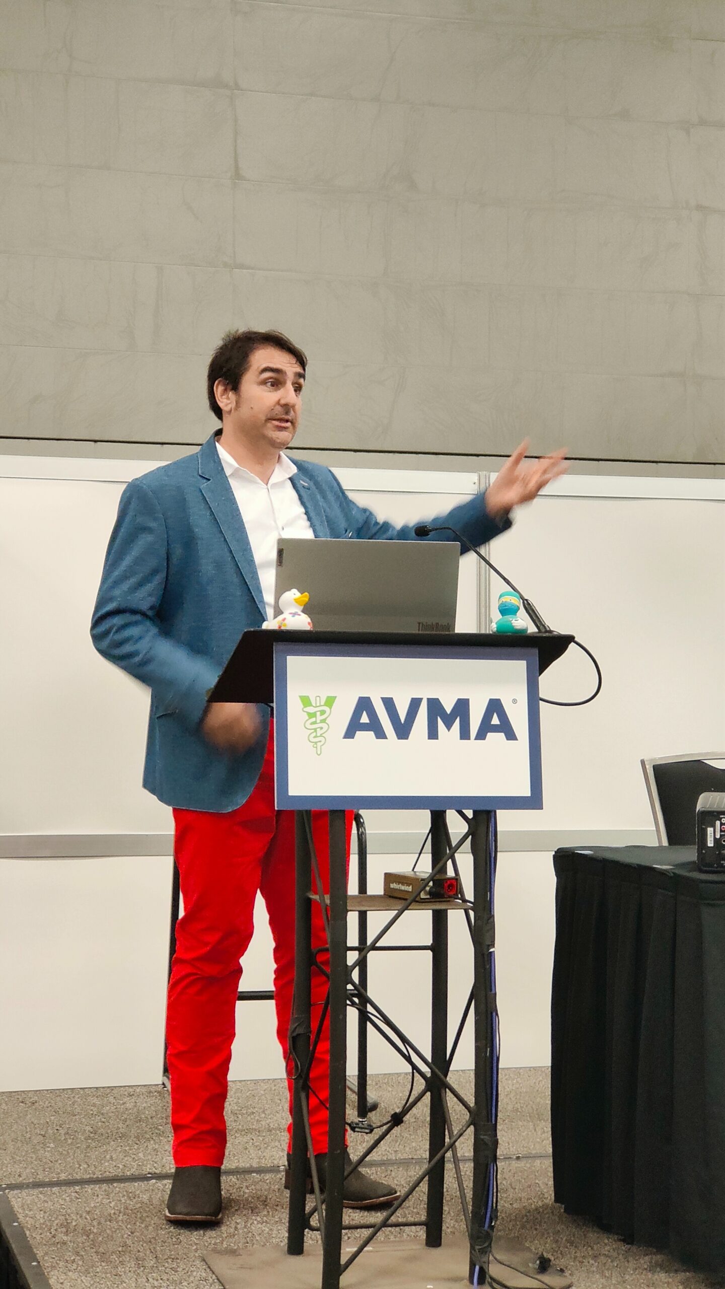 Hombre presentando en una conferencia de AVMA con pantalones rojos