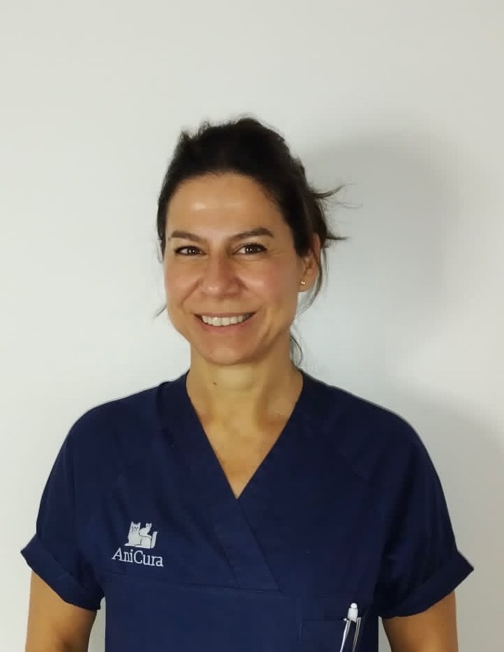 Mujer sonriente con uniforme de AniCura en fondo blanco