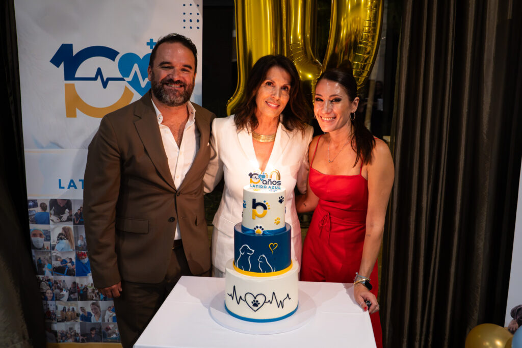Tres personas posan junto a una tarta decorada con el texto diez años Latido Azul
