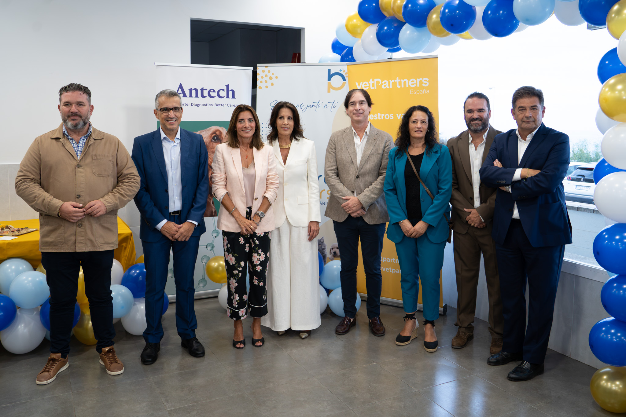 Ocho personas posan ante carteles de Antech y vetPartners con globos azules y dorados.