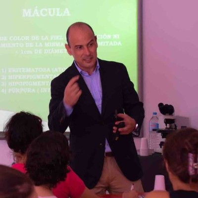 Hombre de pie habla ante una diapositiva mientras varias personas observan.